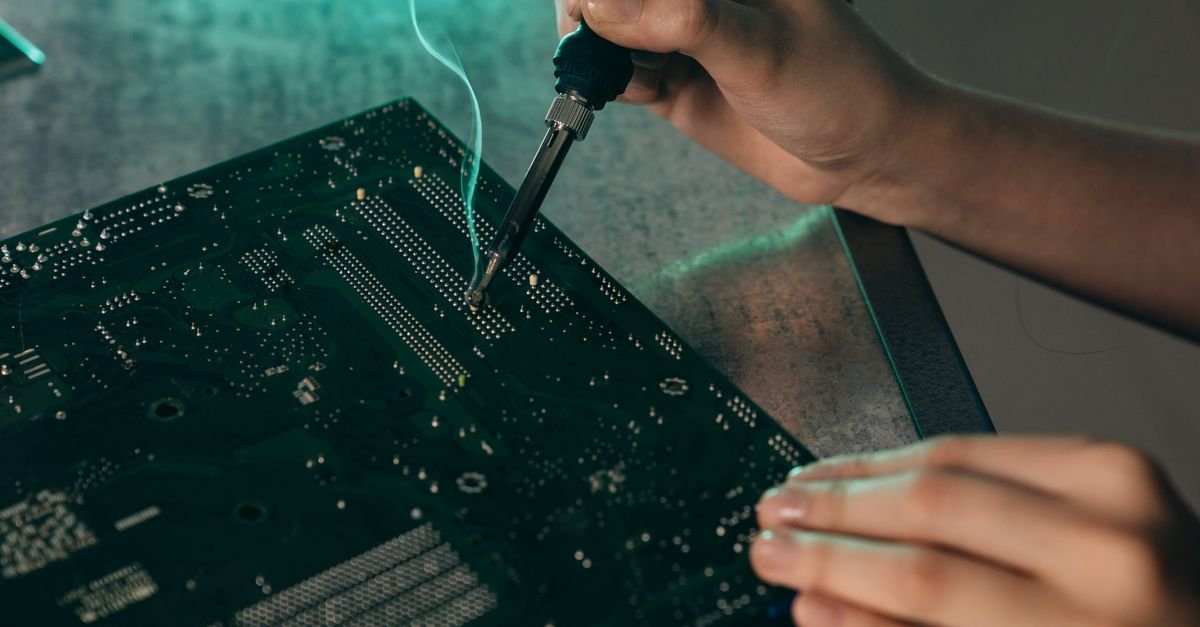 Hände löten Bauteile auf einer Platine