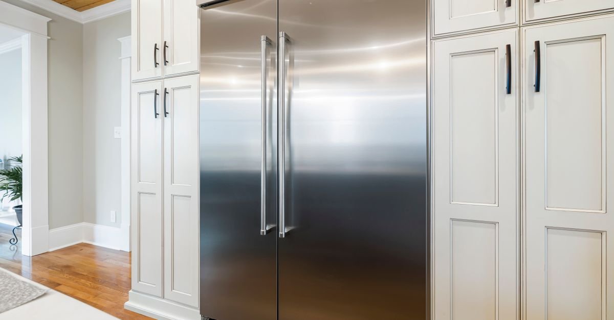 Helle Küche mit Kühlschrank aus Edelstahl zwischen Schränken